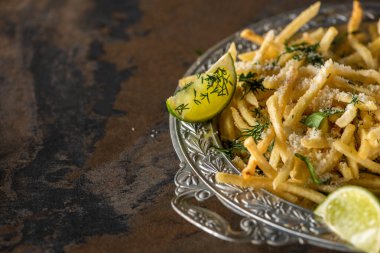Tuzlu patates kızartması ve mermer yüzeyde dilimlenmiş limon seçici odak noktası. 