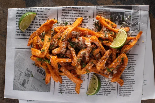 Top view of salty french fries and sliced lime on newspaper with text — Stock Image Top View Salty French Fries Sliced Lime Newspaper Text Royalty Free Stock Images