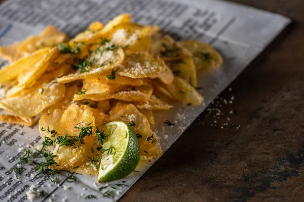 Selective focus of potato chips with salt near sliced lime and newspaper on marble surface — Stock Image Selective Focus Potato Chips Salt Sliced Lime Newspaper Marble Surface Royalty Free Stock Images