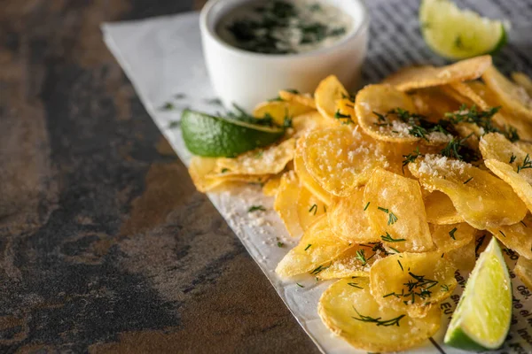 Selective focus of potato chips near lime, garlic sauce and newspaper on marble surface — Stock Image Selective Focus Potato Chips Lime Garlic Sauce Newspaper Marble Surface Stock Image