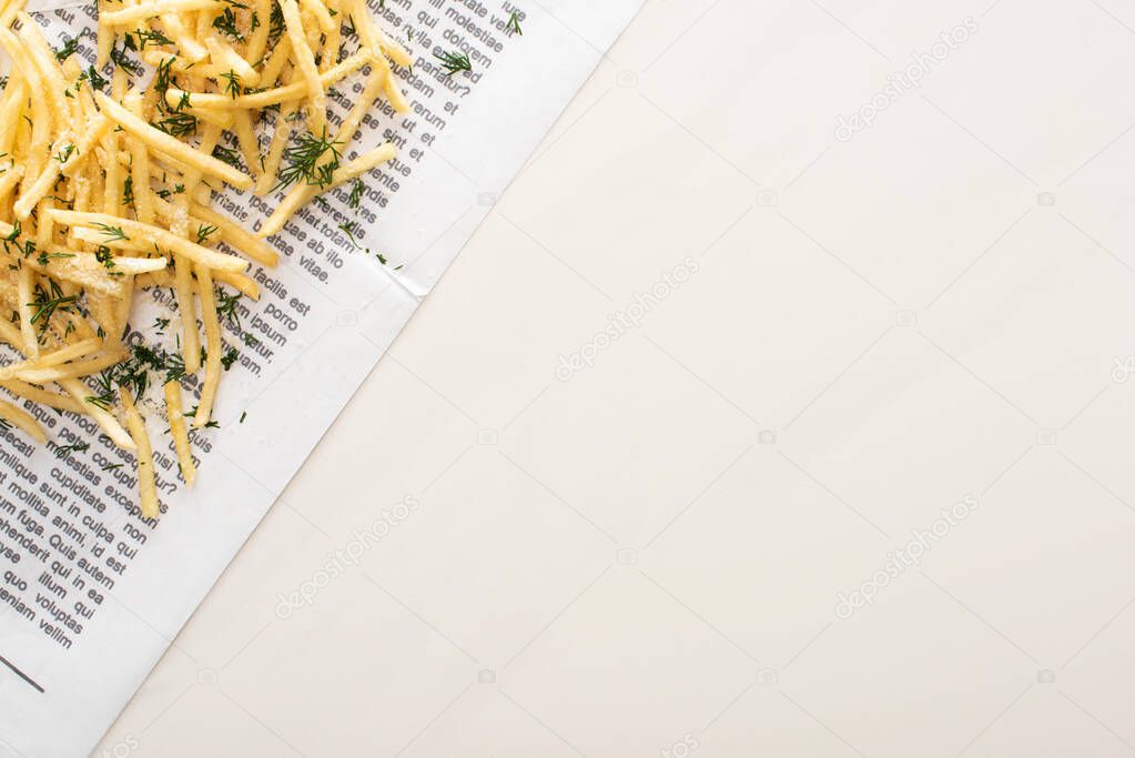 top view of crispy french fries with dill on newspaper on white 