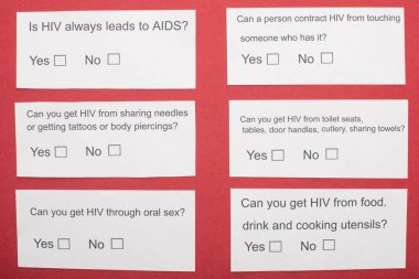 Kırmızı zemin üzerinde HIV anketi olan kağıt kartların üst görünümü