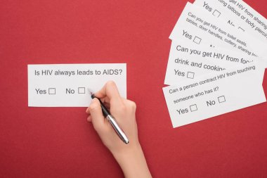Kırmızı arka planda HIV anketine cevap veren kadının kısmi görüntüsü