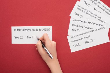 partial view of woman answering HIV questionnaire on red background clipart