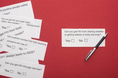 top view of paper cards with HIV questionnaire and pen on red background clipart