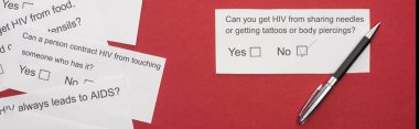top view of paper cards with HIV questionnaire and pen on red background, panoramic shot clipart