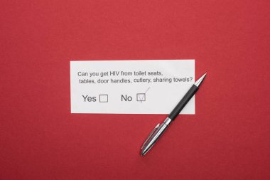 top view of paper card with HIV questionnaire and pen on red background clipart