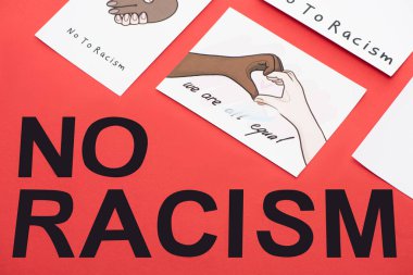 top view of black no racism lettering among pictures with multiethnic hands on red background clipart