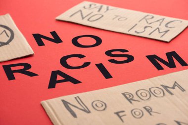 black no racism lettering among carton placards on red background