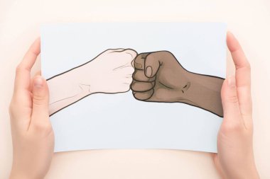 cropped view of woman holding picture with drawn multiethnic hands doing fist bump on beige background clipart