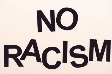 top view of black no racism lettering isolated on beige clipart