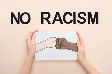 cropped view of woman holding picture with drawn multiethnic hands doing fist bump near no racism lettering on beige background clipart