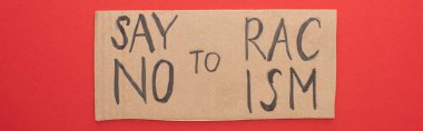 top view of carton placard with say no to racism lettering on red background, panoramic shot clipart