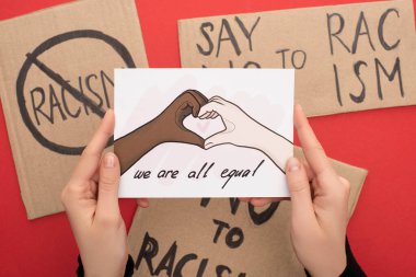 cropped view of woman holding picture with drawn multiethnic hands showing heart gesture on red background with placards clipart