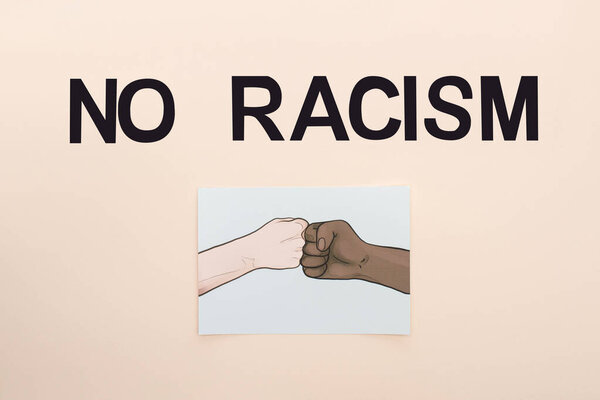 top view of black no racism lettering and picture with drawn multiethnic hands doing fist bump on beige background
