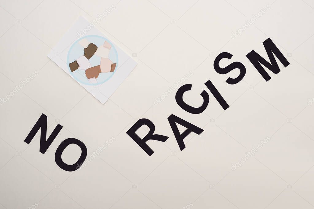 top view of black no racism lettering and picture with multiethnic hands on white background
