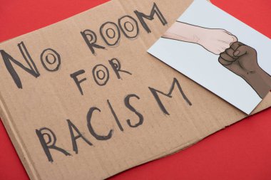 carton placard with say no room for racism lettering and picture with drawn multiethnic hands doing fist bump on red background clipart