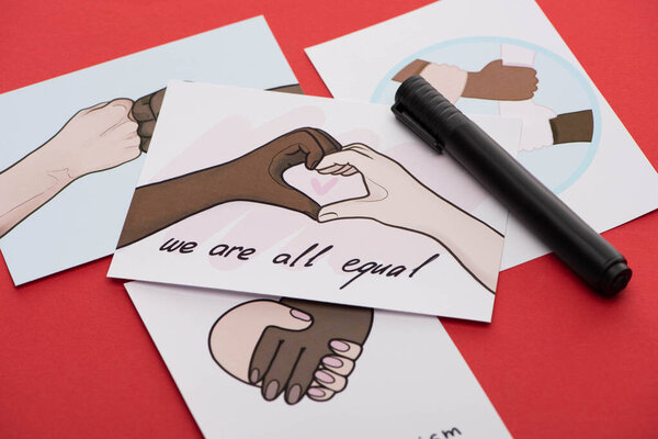 close up view of marker and pictures with multiethnic hands on red background