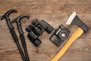 Tahta yüzey üzerinde yürüyüş direkleri, dürbünler, fotoğraf makinesi ve baltanın üst görüntüsü