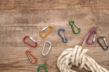 top view of colorful carabiners and hiking rope on wooden table clipart