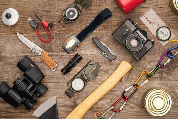 top view of photo camera, tin cans and hiking equipment on wooden surface