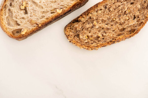 top view of fresh brown bread slices on white background