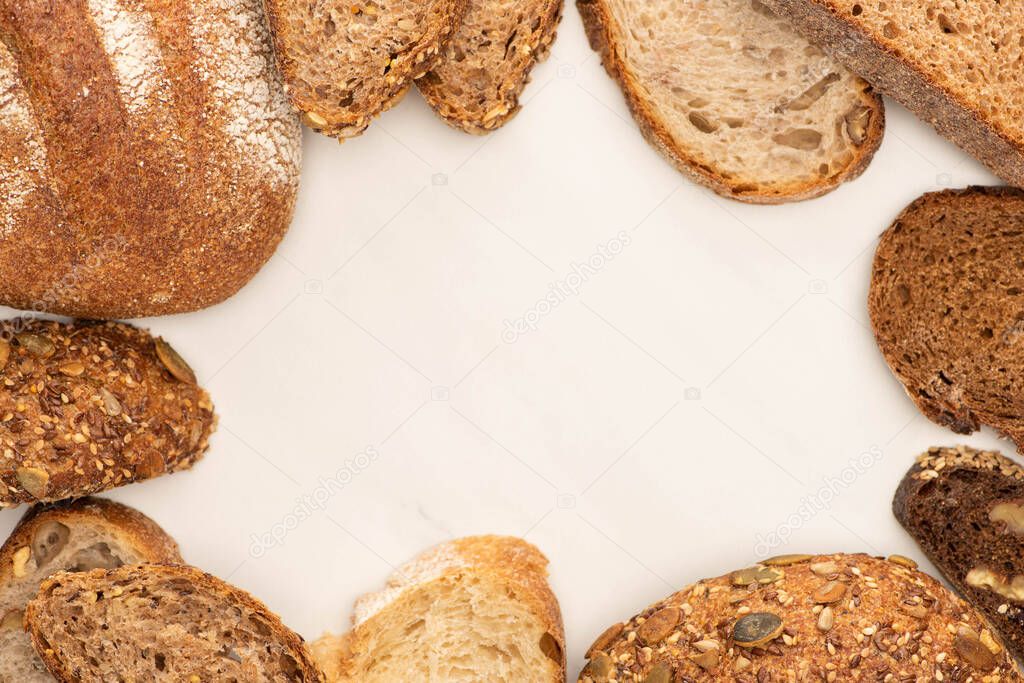 top view of fresh brown bread slices and loaves on white background