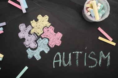 top view of chalks on board with word autism and puzzle drawing  clipart