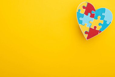 top view of colorful heart with puzzle on yellow for World Autism Awareness Day clipart