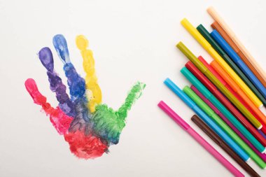 Dünya Otizm Farkındalık Günü için beyaz üzerine renkli el izleri ve düz kalemlerin üst görünümü