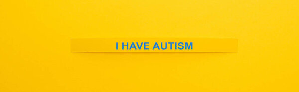 panoramic shot of bracelet with I have autism inscription isolated on yellow