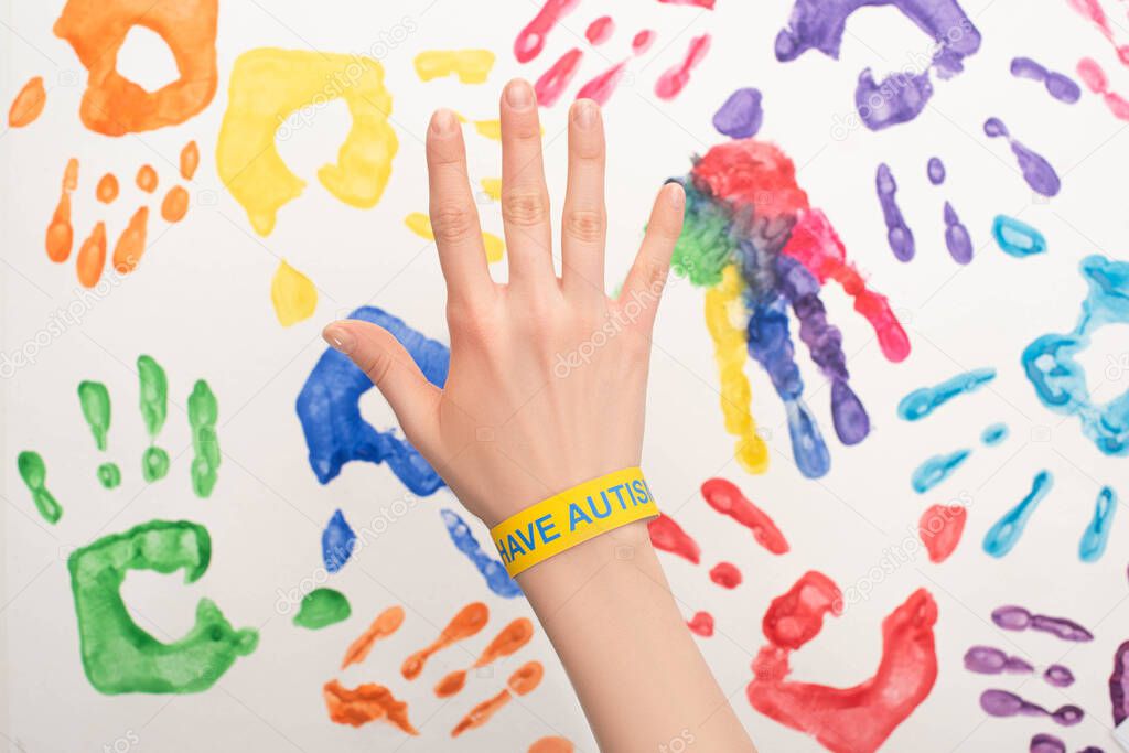 cropped view of female hand with autism bracelet on white with hand prints
