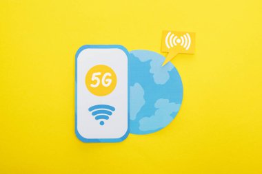 top view of 5g lettering on paper smartphone near globe on yellow background clipart