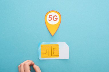 Kadın elinin üst görünümü, sim kart ve mavi arkaplanda 5G harfleri