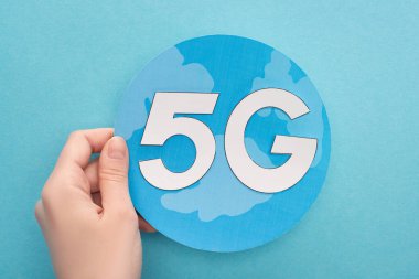 Kırpılmış görüntüde, mavi arka planda beyaz 5g harfli bir kadın var.