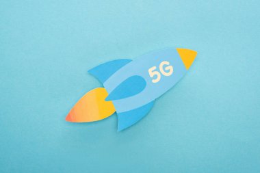 Mavi arkaplanda 5G harfli kağıt roketin üst görünümü