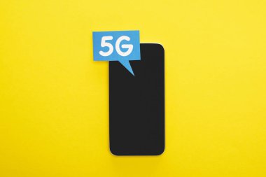 Sarı arka planda akıllı telefonun yanında 5 G harfli konuşma baloncuğunun üst görünümü