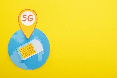 Sim kartın üst görünümü ve sarı arkaplanda dünya üzerindeki 5G harfleri