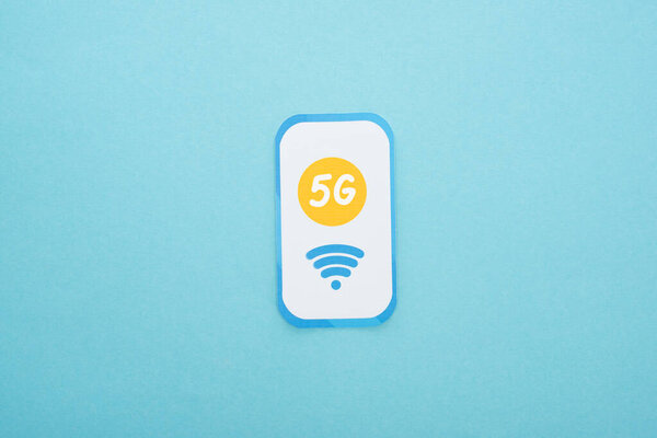 top view of 5g lettering on paper smartphone on blue background