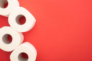 Kırmızı arkaplandaki beyaz tuvalet kağıdı rulolarının üst görünümü