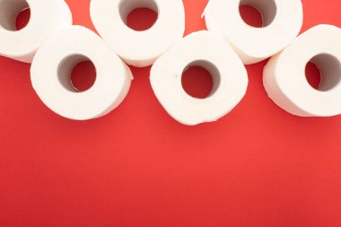 Kırmızı arkaplandaki beyaz tuvalet kağıdı rulolarının üst görünümü