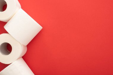 Kırmızı arkaplandaki beyaz tuvalet kağıdı rulolarının üst görünümü