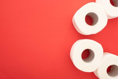 Kırmızı arkaplandaki beyaz tuvalet kağıdı rulolarının üst görünümü