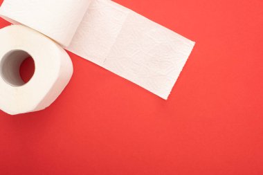 Kırmızı arkaplandaki beyaz tuvalet kağıdı rulolarının üst görünümü