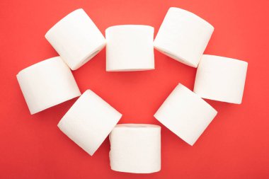 top view of white toilet paper rolls arranged in heart on red background clipart