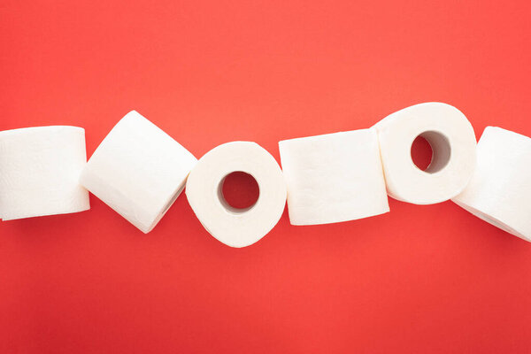 top view of clean toilet paper rolls on red background