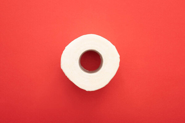 top view of white clean toilet paper roll on red background