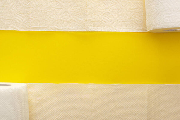 top view of unrolled white toilet paper on yellow background with copy space