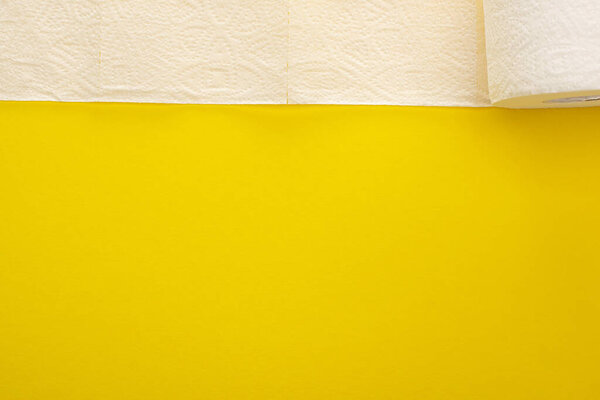 top view of unrolled white toilet paper on yellow background