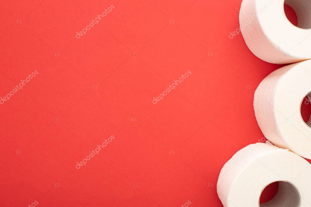top view of white toilet paper rolls on red background with copy space
